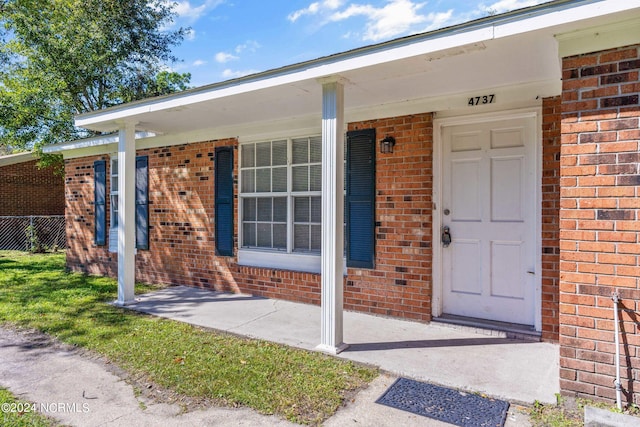 property entrance featuring a porch and brick siding