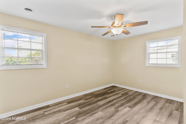 unfurnished room featuring ceiling fan, wood-type flooring, and plenty of natural light