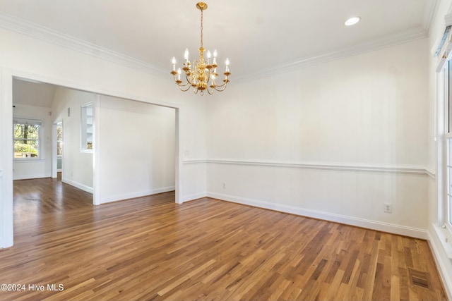 spare room with hardwood / wood-style floors, ornamental molding, and an inviting chandelier