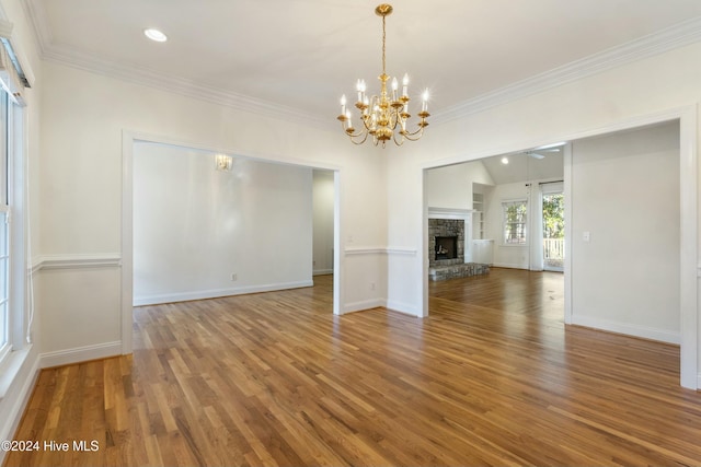 unfurnished living room featuring a fireplace, wood-type flooring, an inviting chandelier, and crown molding