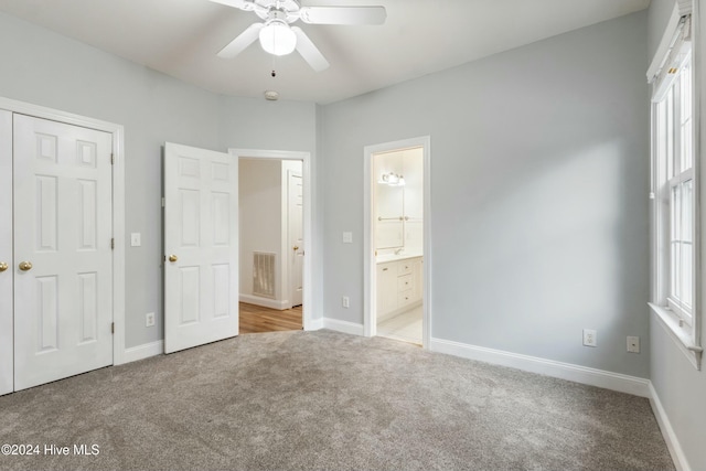 unfurnished bedroom with ceiling fan, ensuite bathroom, light carpet, and multiple windows