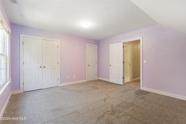 unfurnished bedroom featuring carpet and vaulted ceiling