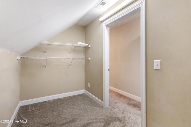 spacious closet with light colored carpet and vaulted ceiling