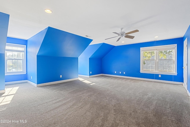 additional living space with a healthy amount of sunlight, light colored carpet, ceiling fan, and lofted ceiling