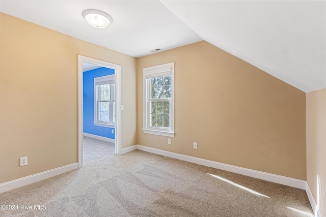 bonus room with lofted ceiling and light carpet