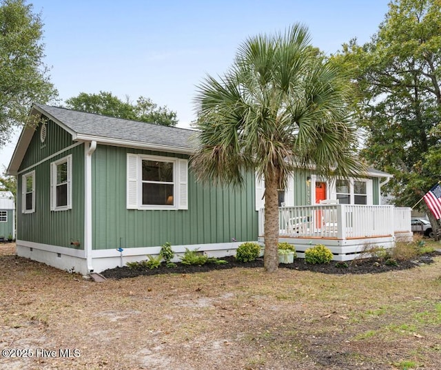 146 NE 5th St, Oak Island, NC 28465 - view of side of home with board and batten siding, cooling unit, a wooden deck, and roof with shingles