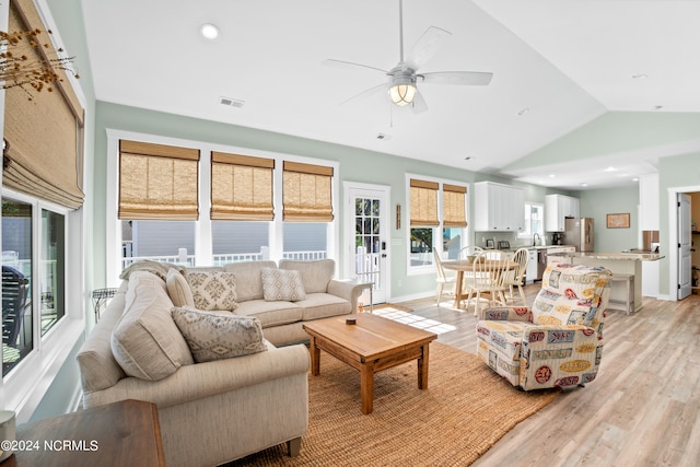 living room with ceiling fan, vaulted ceiling, and light hardwood / wood-style flooring