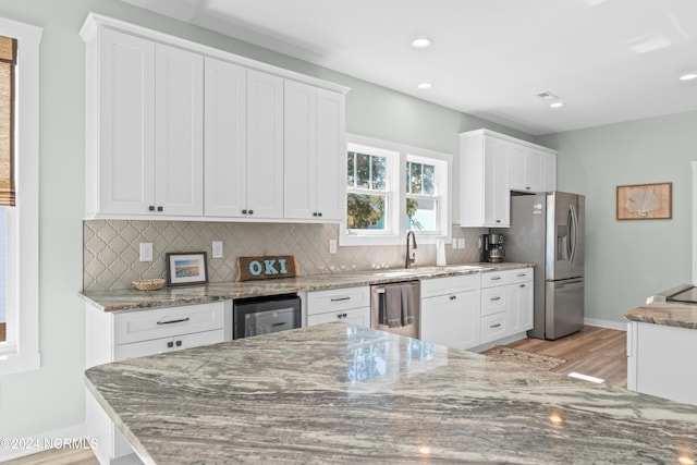 kitchen featuring light stone countertops, stainless steel appliances, and white cabinetry