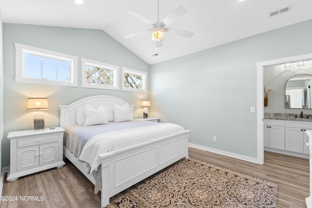 bedroom with ceiling fan, hardwood / wood-style flooring, connected bathroom, and vaulted ceiling