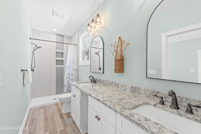 bathroom with wood-type flooring, walk in shower, vanity, and toilet