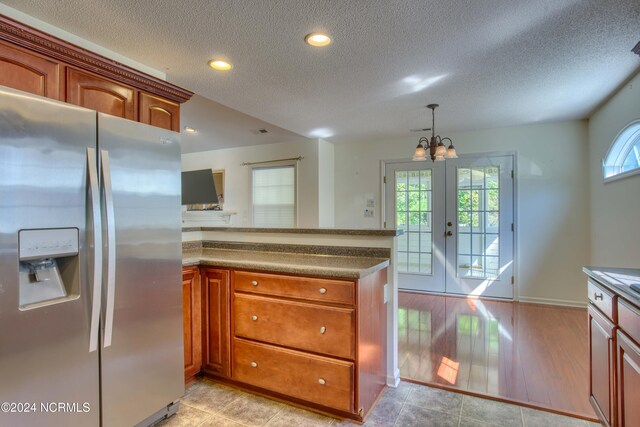 kitchen featuring french doors, stainless steel fridge with ice dispenser, a chandelier, pendant lighting, and a textured ceiling