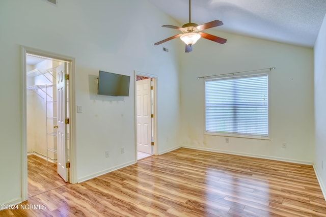 unfurnished room featuring a textured ceiling, ceiling fan, light hardwood / wood-style floors, and vaulted ceiling