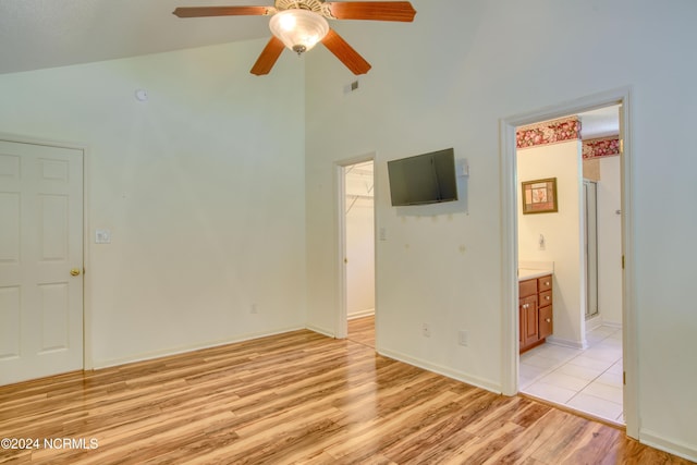 empty room with ceiling fan, light hardwood / wood-style floors, and vaulted ceiling