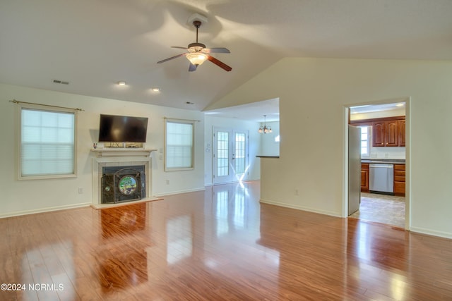 unfurnished living room featuring ceiling fan with notable chandelier, light hardwood / wood-style flooring, and lofted ceiling