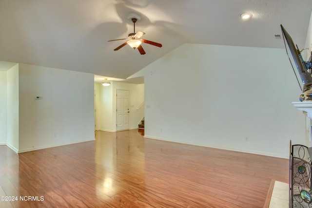 unfurnished living room featuring light hardwood / wood-style floors, ceiling fan, lofted ceiling, and a tiled fireplace