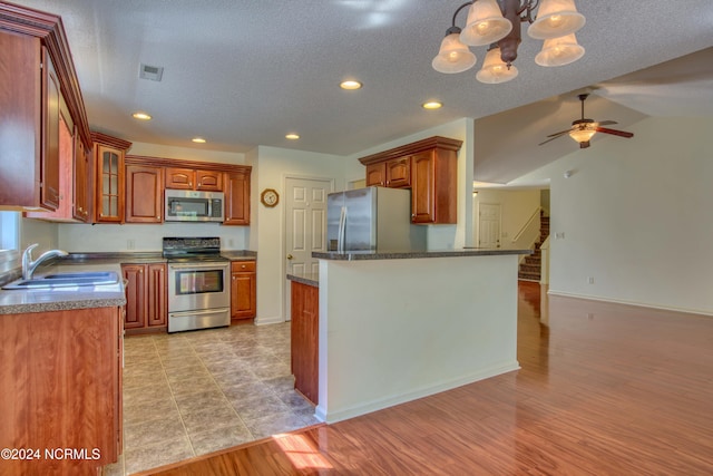 kitchen with ceiling fan with notable chandelier, hanging light fixtures, sink, a textured ceiling, and appliances with stainless steel finishes