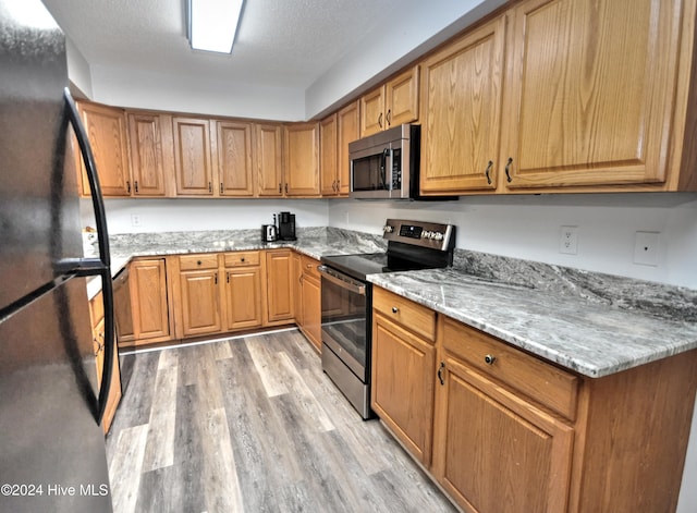 4746 Rail Ct SW, Shallotte, NC 28470 - kitchen featuring appliances with stainless steel finishes, light wood-type flooring, light stone countertops, and brown cabinets