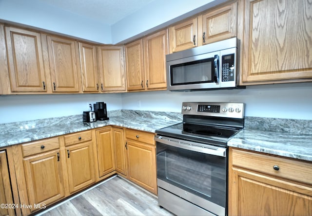 4746 Rail Ct SW, Shallotte, NC 28470 - kitchen with stainless steel appliances, light wood-style flooring, and light stone counters
