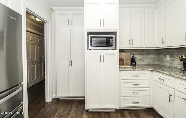 kitchen featuring light stone countertops, appliances with stainless steel finishes, white cabinetry, tasteful backsplash, and crown molding