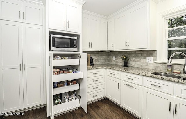 kitchen featuring tasteful backsplash, dark wood-type flooring, white cabinets, light stone counters, and sink