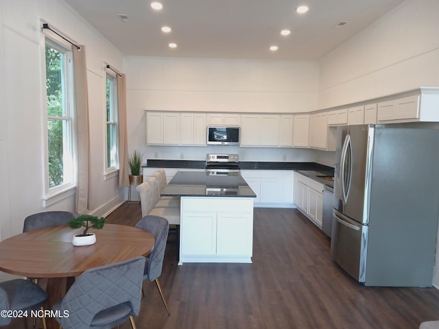 kitchen featuring appliances with stainless steel finishes, dark hardwood / wood-style floors, white cabinets, and a center island