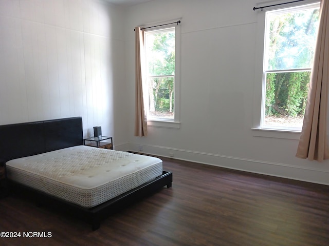 bedroom with multiple windows and dark hardwood / wood-style flooring