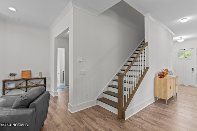 stairs with crown molding and hardwood / wood-style flooring