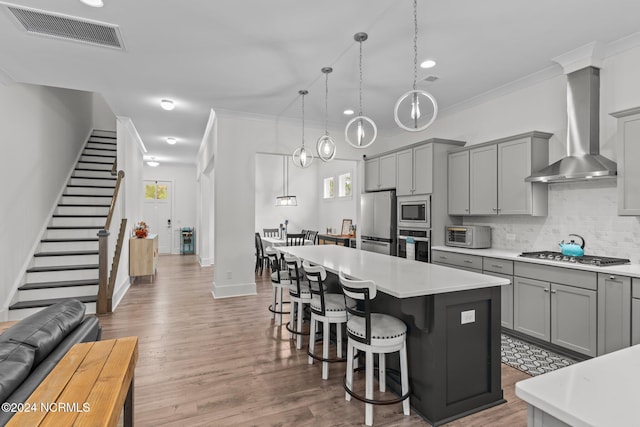 kitchen with a kitchen island, appliances with stainless steel finishes, wall chimney range hood, and plenty of natural light