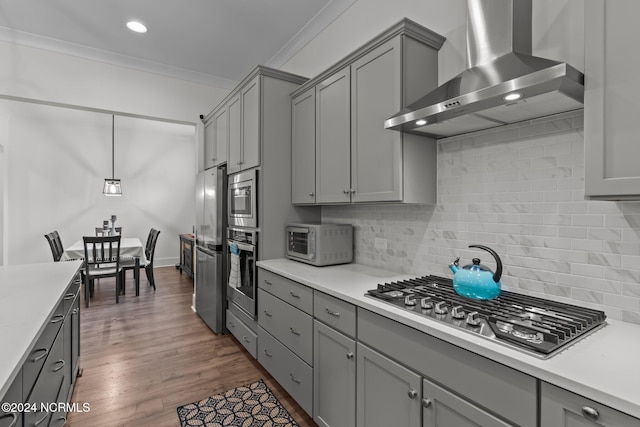 kitchen featuring wall chimney range hood, decorative backsplash, dark hardwood / wood-style floors, pendant lighting, and stainless steel appliances