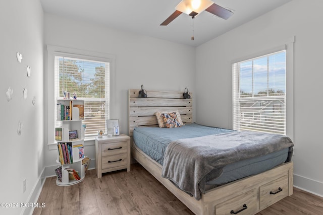 bedroom featuring ceiling fan, multiple windows, and dark hardwood / wood-style floors