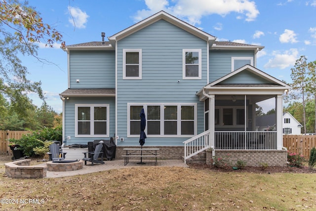 rear view of house with an outdoor fire pit, a yard, a patio, and a sunroom