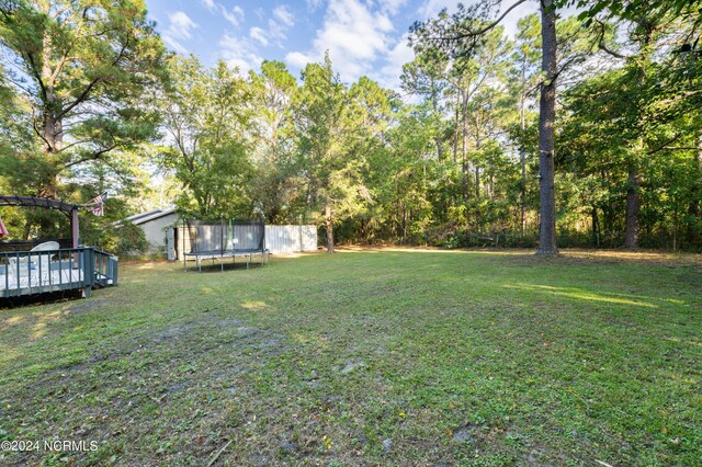 view of yard with a trampoline and a deck