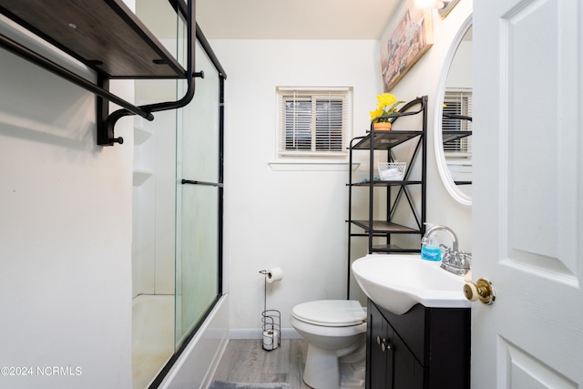 full bathroom featuring vanity, enclosed tub / shower combo, toilet, and wood-type flooring