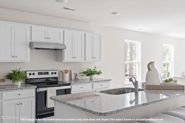 kitchen featuring light stone countertops, a breakfast bar, sink, electric stove, and white cabinetry