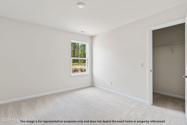 unfurnished bedroom with light colored carpet and a closet