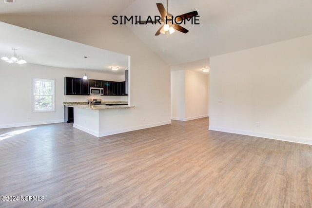 unfurnished living room with high vaulted ceiling, wood-type flooring, and ceiling fan with notable chandelier