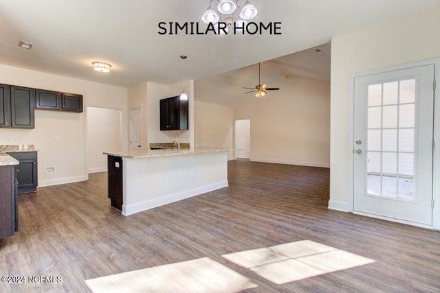 kitchen featuring light stone countertops, hardwood / wood-style floors, ceiling fan, lofted ceiling, and pendant lighting