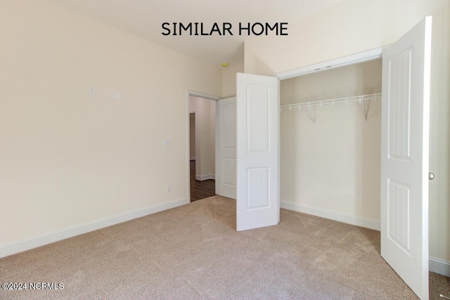 unfurnished bedroom with a closet and light carpet