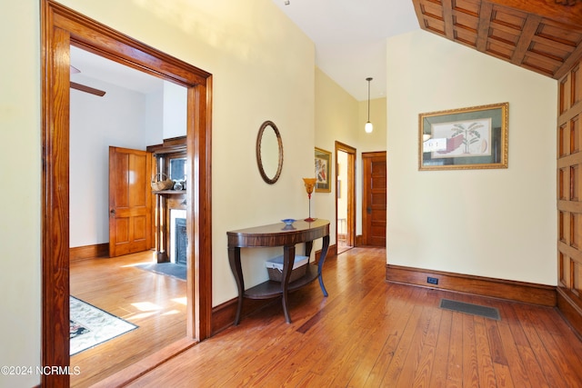 corridor with wood ceiling, high vaulted ceiling, and light wood-type flooring