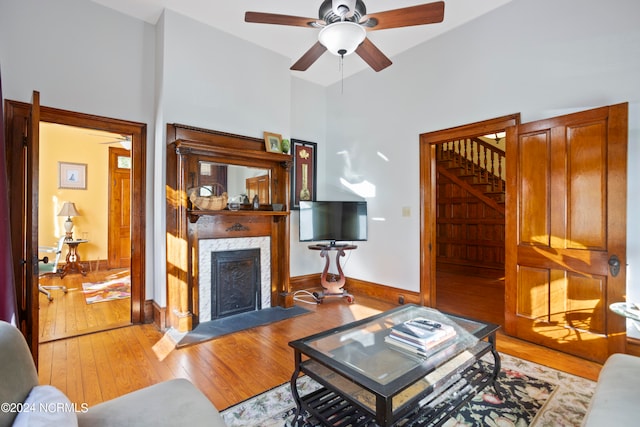 living room with a high end fireplace, high vaulted ceiling, light wood-type flooring, and ceiling fan