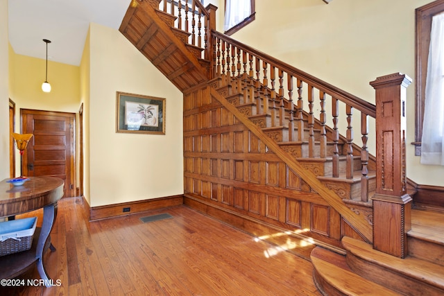 stairs featuring a towering ceiling and wood-type flooring