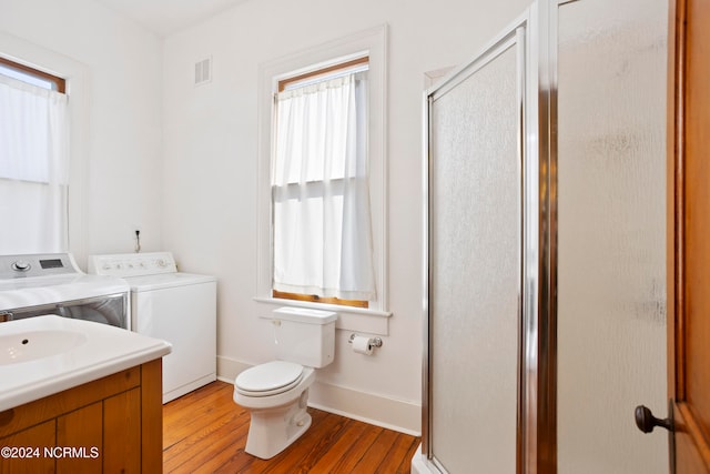 bathroom with vanity, hardwood / wood-style floors, washer and clothes dryer, and a shower with shower door