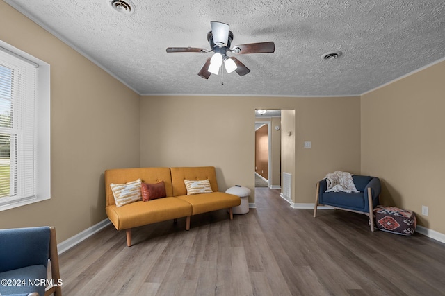 sitting room featuring hardwood / wood-style flooring, crown molding, ceiling fan, and a textured ceiling