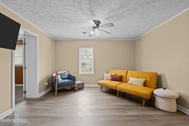 sitting room with crown molding, ceiling fan, wood-type flooring, and a textured ceiling