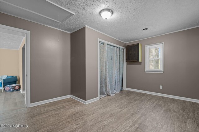 unfurnished bedroom featuring light hardwood / wood-style floors, crown molding, and a textured ceiling