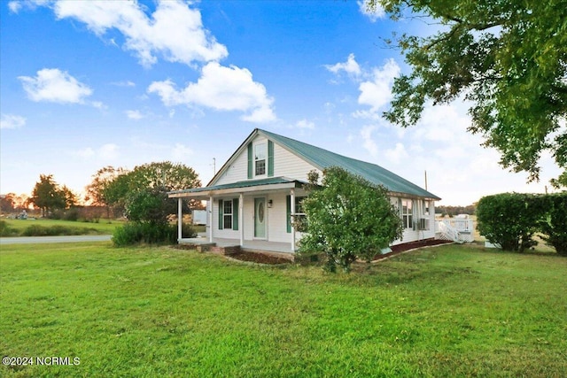 rear view of house with covered porch and a lawn