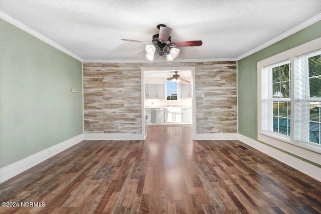 unfurnished living room with dark wood-type flooring, crown molding, a textured ceiling, and a healthy amount of sunlight