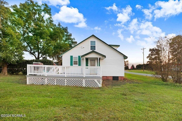 rear view of property with a wooden deck and a lawn