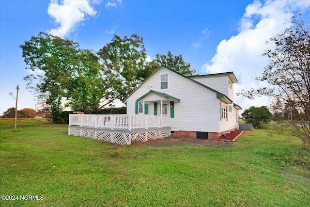 rear view of house featuring a wooden deck and a yard