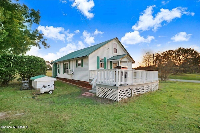 exterior space with a wooden deck, a storage unit, and a front lawn